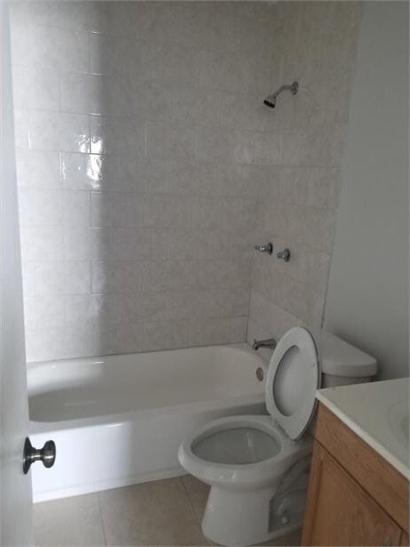 full bathroom featuring vanity, tile patterned flooring, toilet, and tiled shower / bath combo