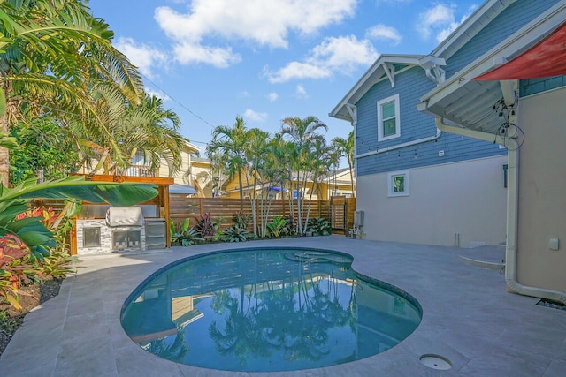 view of swimming pool featuring a patio area and exterior kitchen