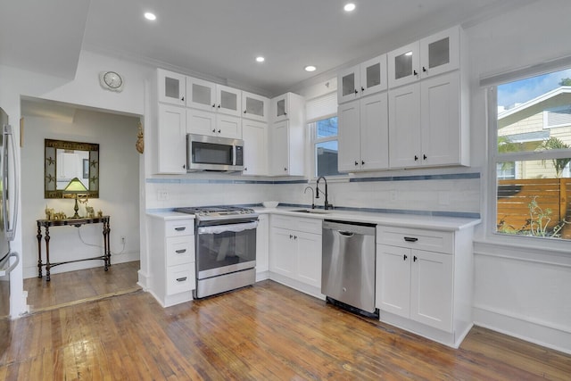 kitchen with stainless steel appliances, white cabinetry, sink, and tasteful backsplash