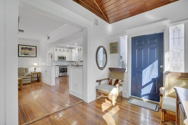 entryway featuring ornamental molding, sink, wooden ceiling, and light hardwood / wood-style flooring