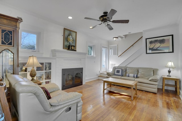 living room with ceiling fan, a brick fireplace, and light wood-type flooring