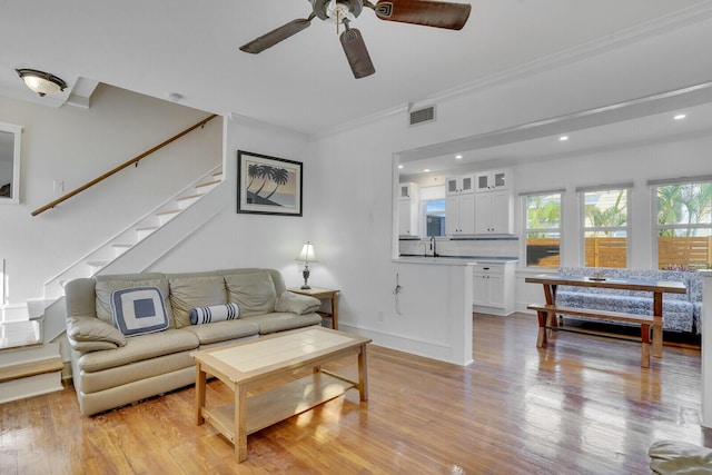 living room featuring crown molding, light hardwood / wood-style floors, and ceiling fan