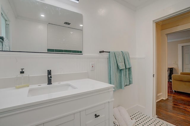 bathroom featuring hardwood / wood-style flooring, vanity, ornamental molding, and walk in shower