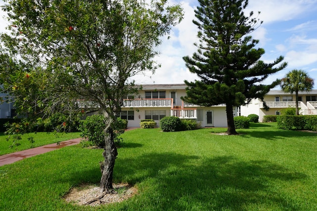 view of front of house with a balcony and a front yard