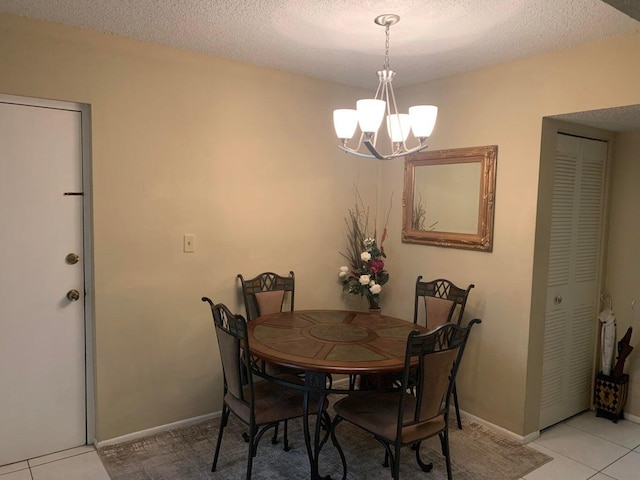 tiled dining space with a textured ceiling and a chandelier