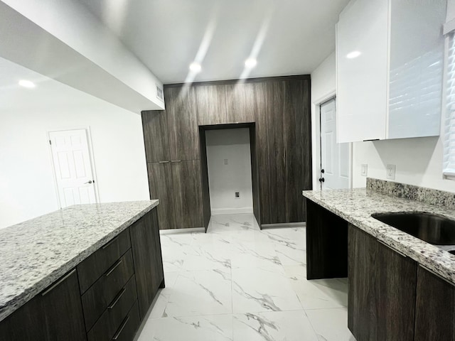 kitchen with light stone countertops, marble finish floor, recessed lighting, and modern cabinets