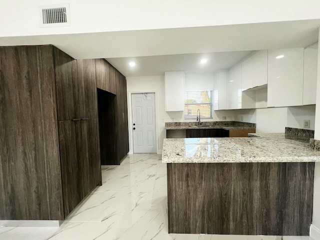 kitchen with a peninsula, marble finish floor, modern cabinets, and visible vents