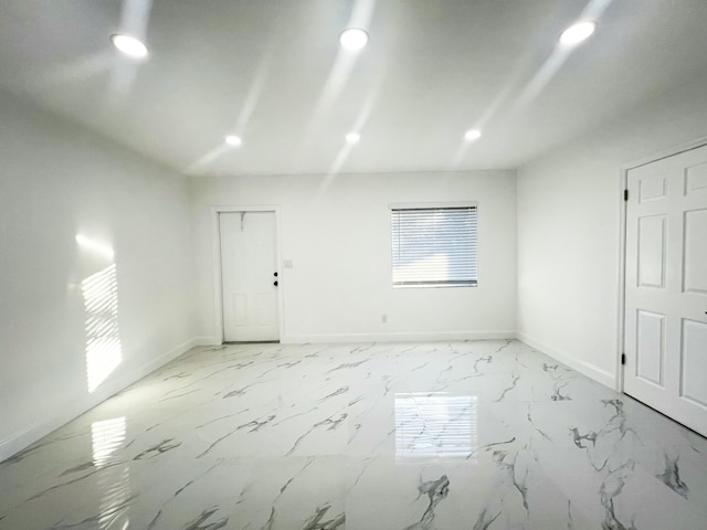 empty room featuring baseboards, marble finish floor, and recessed lighting