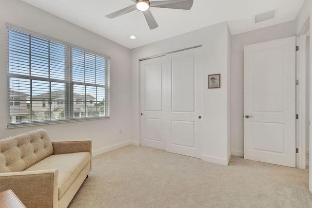 living area featuring light colored carpet and ceiling fan