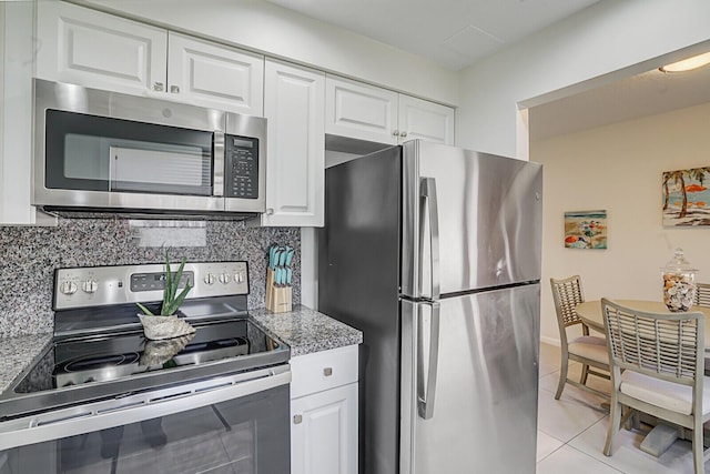 kitchen featuring appliances with stainless steel finishes, light tile patterned floors, decorative backsplash, and white cabinets