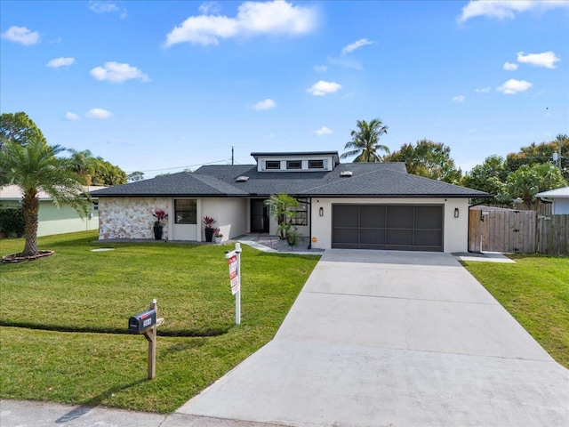 view of front of property with concrete driveway, an attached garage, fence, and a front yard