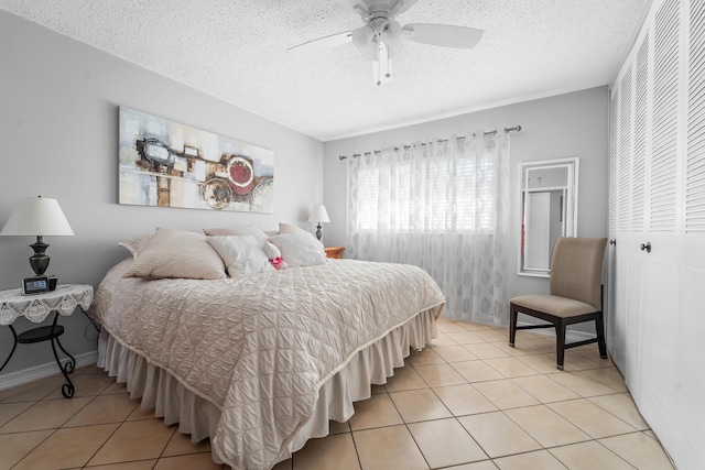 tiled bedroom with ceiling fan, a textured ceiling, and a closet