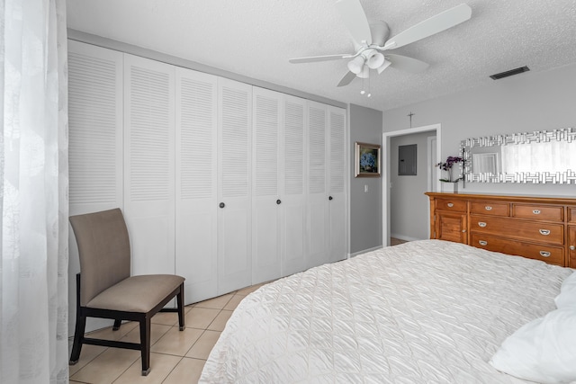 tiled bedroom featuring ceiling fan, a textured ceiling, and a closet