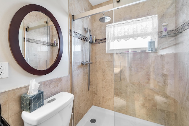 bathroom with tiled shower, toilet, and tile walls