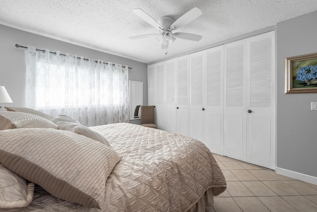 tiled bedroom with ceiling fan, a textured ceiling, and a closet