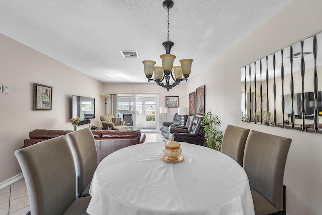 dining space featuring light tile patterned floors, a chandelier, and a textured ceiling