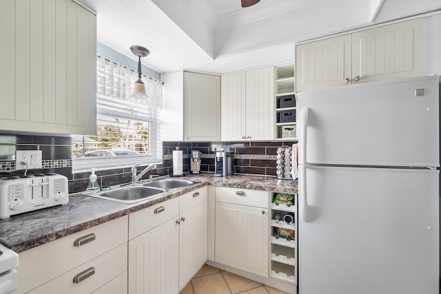 kitchen with decorative light fixtures, tasteful backsplash, sink, white fridge, and light tile patterned floors