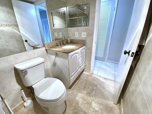 bathroom featuring tile walls, vanity, tile patterned floors, and toilet