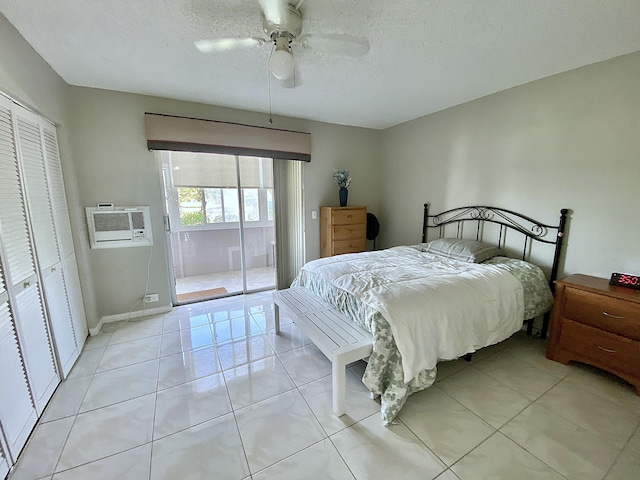 tiled bedroom featuring a wall mounted air conditioner, access to outside, ceiling fan, a textured ceiling, and a closet