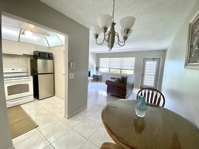 dining space featuring ceiling fan with notable chandelier, a textured ceiling, and light tile patterned floors