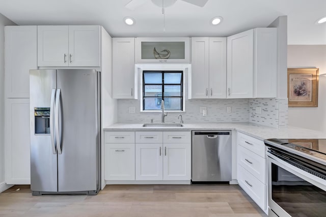 kitchen featuring sink, white cabinets, decorative backsplash, light hardwood / wood-style floors, and stainless steel appliances