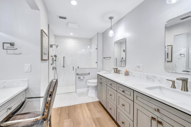 bathroom with hardwood / wood-style flooring, vanity, toilet, and a shower with door