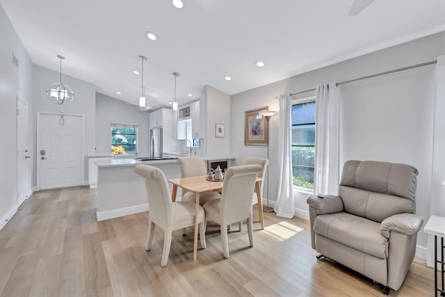 dining room with a wealth of natural light, light hardwood / wood-style floors, and vaulted ceiling