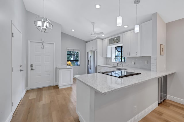 kitchen featuring stainless steel refrigerator with ice dispenser, white cabinetry, and kitchen peninsula