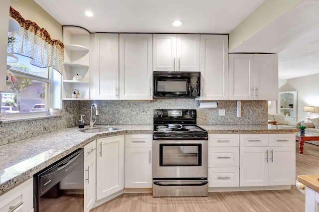 kitchen with sink, backsplash, white cabinets, light stone counters, and black appliances