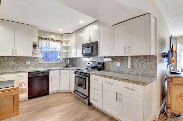 kitchen featuring white cabinetry, light stone countertops, and black appliances