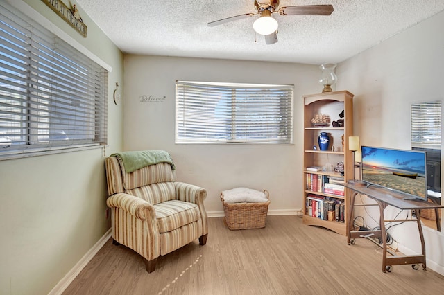 sitting room with ceiling fan, light hardwood / wood-style flooring, and a textured ceiling