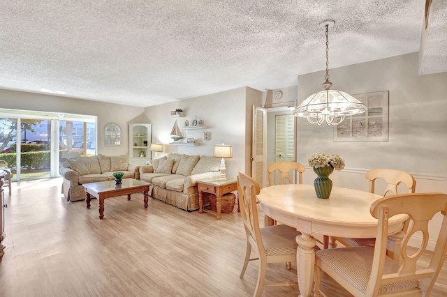 dining space featuring wood-type flooring, a chandelier, and a textured ceiling