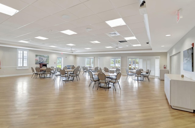 dining space with a tray ceiling, a healthy amount of sunlight, a paneled ceiling, and light hardwood / wood-style flooring