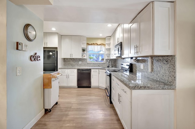 kitchen featuring white cabinetry, backsplash, black appliances, light stone countertops, and light wood-type flooring