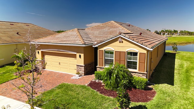 view of front of property with decorative driveway, stucco siding, an attached garage, a front yard, and stone siding