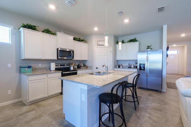 kitchen with appliances with stainless steel finishes, a breakfast bar area, a kitchen island with sink, a sink, and recessed lighting