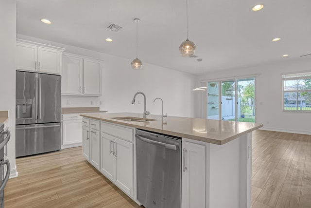 kitchen with white cabinetry, stainless steel appliances, sink, and hanging light fixtures