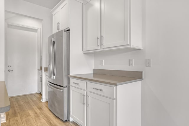 kitchen featuring stainless steel refrigerator, white cabinetry, and light wood-type flooring