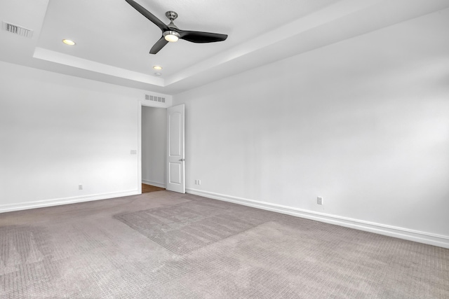 carpeted empty room with a tray ceiling and ceiling fan