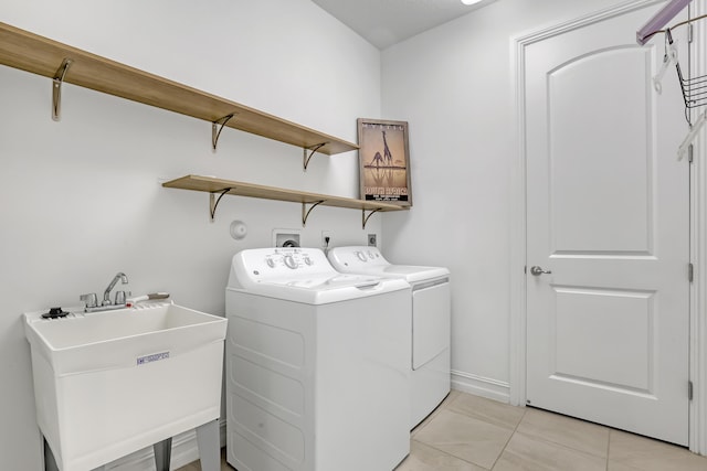 clothes washing area featuring washer and clothes dryer, sink, and light tile patterned floors