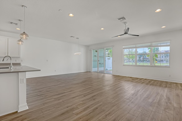 unfurnished living room with sink and light hardwood / wood-style floors