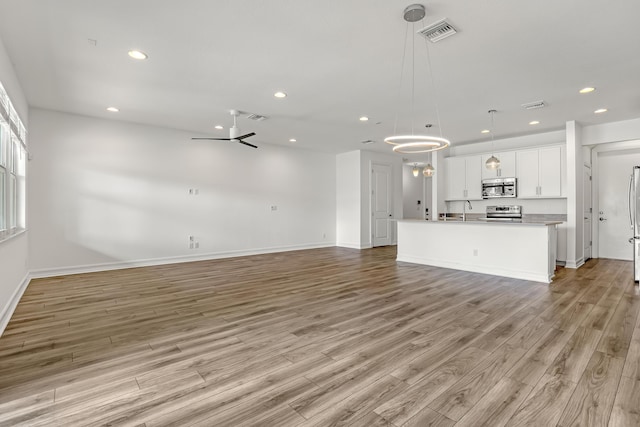 unfurnished living room featuring sink and light hardwood / wood-style floors