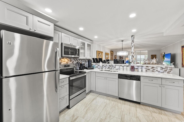 kitchen featuring appliances with stainless steel finishes, kitchen peninsula, sink, and hanging light fixtures