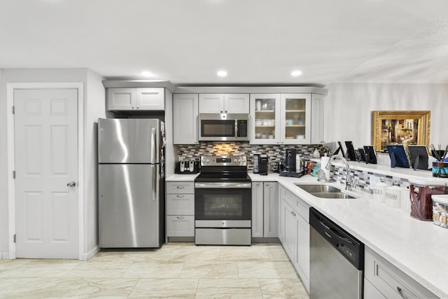 kitchen with sink, gray cabinets, stainless steel appliances, light stone counters, and decorative backsplash