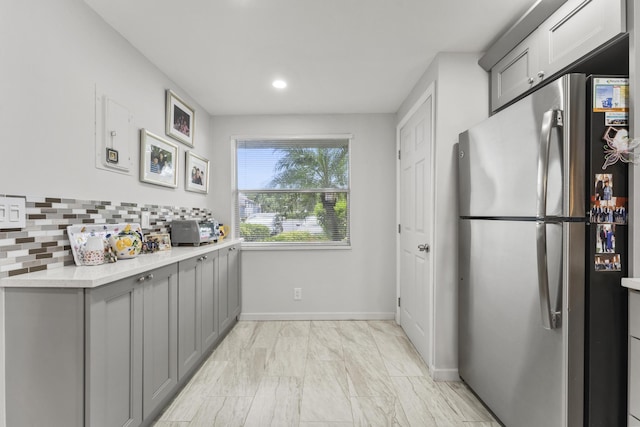 kitchen featuring gray cabinetry, decorative backsplash, and stainless steel fridge