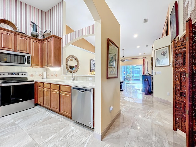 kitchen featuring sink, decorative backsplash, ceiling fan, and appliances with stainless steel finishes