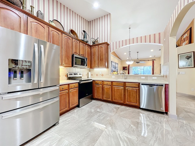 kitchen with pendant lighting, sink, decorative backsplash, and stainless steel appliances