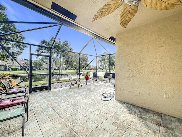 view of patio featuring a water view and glass enclosure