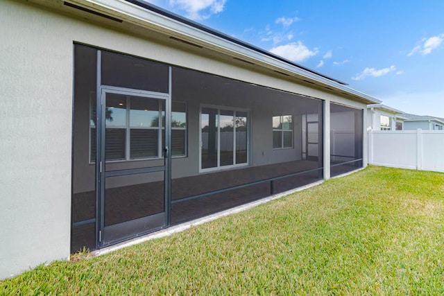 rear view of property featuring a lawn and a sunroom