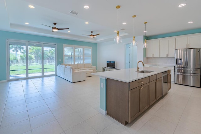 kitchen featuring pendant lighting, sink, stainless steel appliances, a tray ceiling, and white cabinets